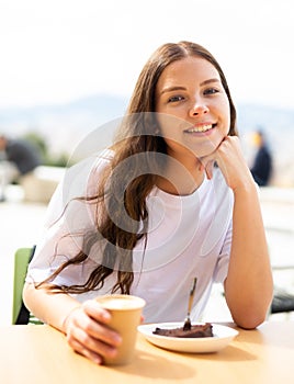 Portrait of a positive girl sitting at a table with a cup of delicious coffee photo
