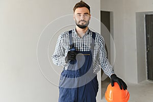 Portrait of positive, handsome young male builder in hard hat