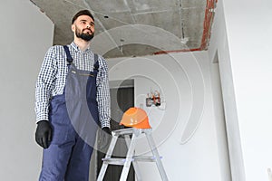 Portrait of positive, handsome young male builder in hard hat