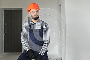 Portrait of positive, handsome young male builder in hard hat