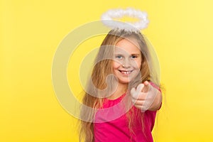 Portrait of positive happy little girl with long fair hair and angelic halo pointing finger, making choice