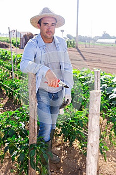 Portrait of positive hired worker on farm field on day
