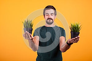 Portrait of positive man in serenity state of mind holds two pots with green grass