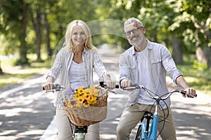 Portrait Of Positive Mature Couple Cycling Together In Summer Park