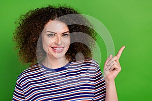 Portrait of positive nice girl toothy smile indicate finger empty space ad isolated on green color background