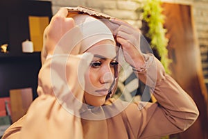 Portrait of positive pretty young Arabian woman in pink headscarf touching face with hand.