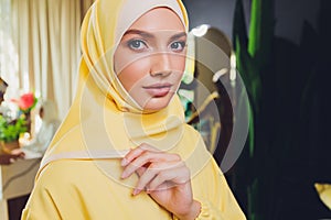 Portrait of positive pretty young Arabian woman in pink headscarf touching face with hand.