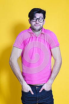 Portrait of Positive Smiling Caucasian Handsome Man Posing in Pink Shirt And Glasses in Casual Style Against Yellow Background.