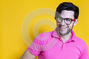 Portrait of Positive Smiling Caucasian Handsome Man Posing in Pink Shirt And Glasses in Casual Style Against Yellow Background.