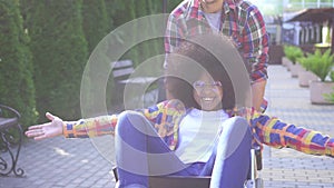 Portrait of a positive smiling young African American woman disabled in a wheelchair and her friend rejoices and raises