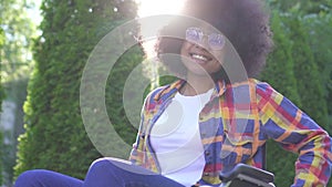 Portrait of a positive smiling young African American woman disabled in a wheelchair looking at the camera on a Sunny