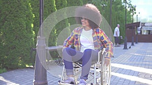 Portrait of a positive smiling young African American woman disabled in a wheelchair on the street