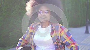 Portrait of positive smiling young African American woman disabled in a wheelchair in Sunny Park