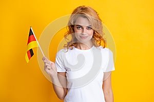 Portrait of positive student woman holding German flag. Isolated on yellow background. Happy girl holding flag of