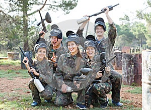 Portrait of positive team of paintball players with marker guns outdoors