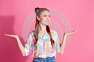 Portrait of positive woman with foxy hairstyle wear print shirt look at best option on arm empty space isolated on pink