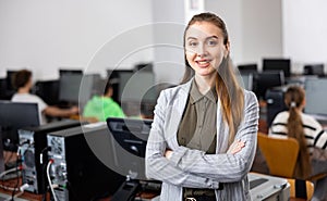 Portrait of positive woman teacher standing in computer class