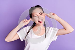 Portrait of positive young lady hands fingers hold pull ears showing tongue out isolate don purple color background