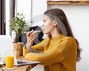 Portrait of positive young woman recording audio message, speaking to microphone