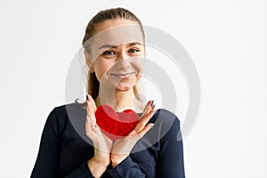 Portrait of a positive young woman with a red heart in her hands, taking care of the human cardiovascular system