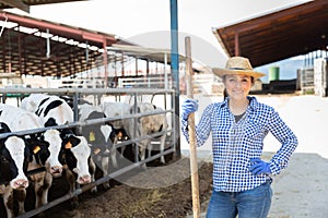 Portrait of a positive young woman standing on a cattle farm