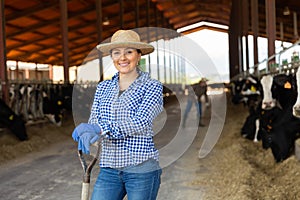 Portrait of a positive young woman standing on a cattle farm