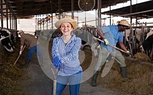 Portrait of a positive young woman standing on a cattle farm