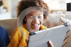 Portrait of pre-teen girl looking at tablet computer screen laughing, close up, selective focus