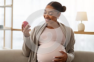 Portrait of pregnant african american woman holding red apple