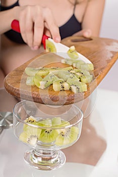 Portrait of pregnant mother cuts kiwi fruit