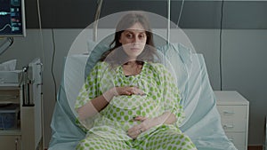 Portrait of pregnant woman laying in hospital ward bed