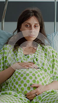 Portrait of pregnant woman laying in hospital ward bed