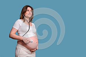 Portrait of a pregnant woman with a medical stethoscope, blue background