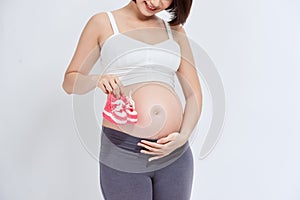A portrait of a Pregnant woman with a pair of pink knit baby shoes