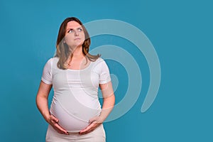 Portrait of a pregnant woman in perplexity on a blue background