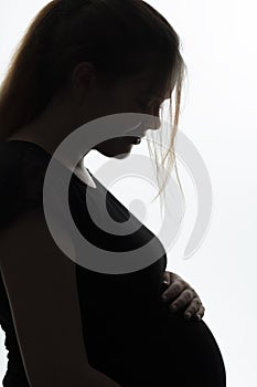 Portrait of pregnant woman in profile with hands on her stomach on a white isolated background, future life concept