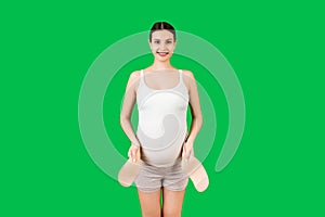 Portrait of pregnant woman in putting on supporting bandage for reducing backache at green background with copy space. Orthopedic