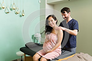 Portrait of a pregnant woman smiling while getting a back massage