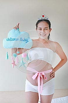 Portrait of pregnant woman wear a crown and holding soft fabric with text `Welcome Baby`