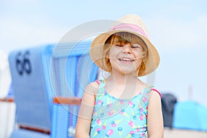 Portrait of preschool girl in colorful swimmsuit and straw hat. Cute happy toddler child on family vacations on the sea