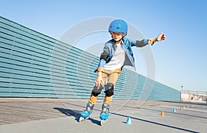 Boy learning to roller skate on road with cones photo