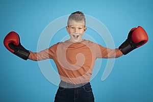Portrait Of Preteen Caucasian Boy Wearing Boxing Gloves Posing Over Blue Background