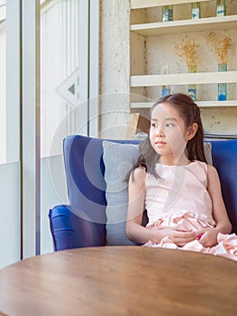 Portrait Of Preteen Girl Sitting On Sofa At Home by the window, look out the window