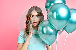 Portrait of pretty amazed woman with balloons on pink background