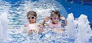 Portrait of pretty asian twins smilling and posing on swimming pool background wearing pink swim suit and sun glasses