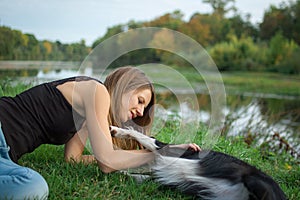 Portrait of pretty attractive girl spending time with her white and black dog outdoors during summer day on river