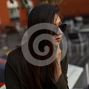 Portrait of a pretty attractive and young brunette girl in shiny black stylish glasses and trendy clothes. Fashionable woman.