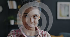 Portrait of pretty biracial girl adorable child standing in apartment smiling looking at camera