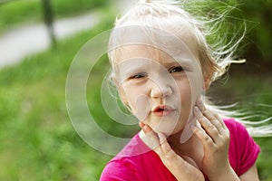 Portrait of pretty blond toddler girl in a windy summer day