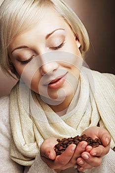 Portrait of pretty blonde girl hold coffee beans in hands